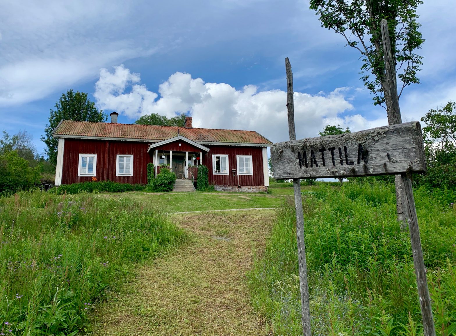 Ett rött hus med en gammal skylt "Mattila"
